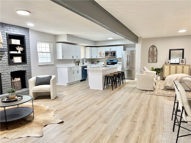 living room with light wood-style floors, beam ceiling, and a fireplace