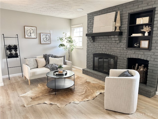 living area featuring a fireplace, baseboards, a textured ceiling, and wood finished floors