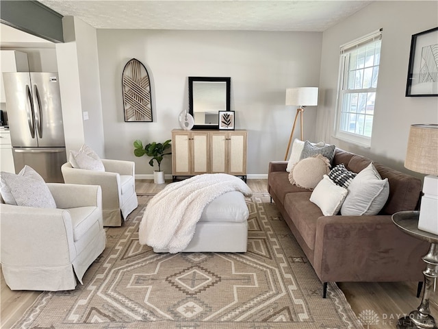 living room with a textured ceiling, light wood finished floors, and baseboards