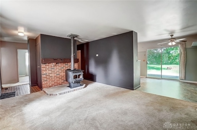 unfurnished living room with a wood stove and ceiling fan