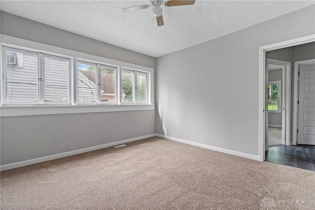 carpeted spare room featuring ceiling fan and a textured ceiling