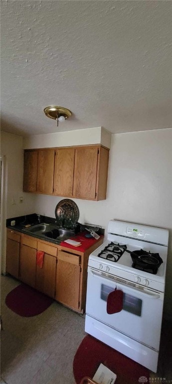 kitchen with sink, a textured ceiling, and white gas stove