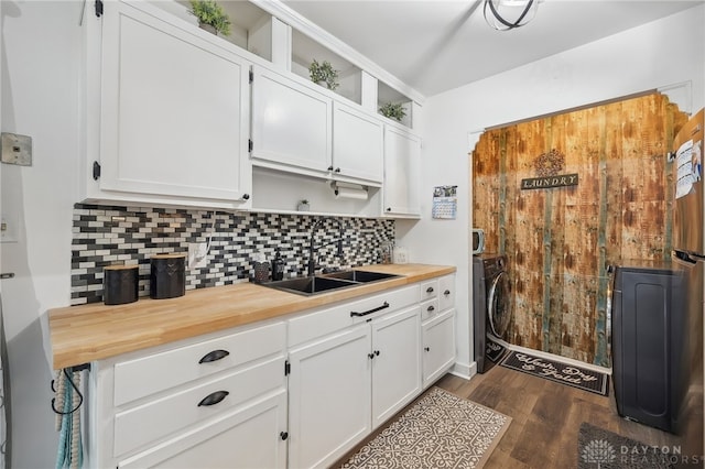 kitchen with backsplash, sink, dark hardwood / wood-style flooring, washer / dryer, and white cabinets