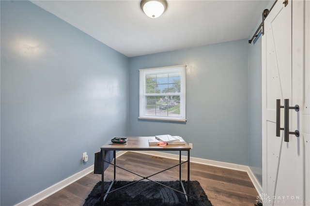 home office with wood-type flooring and a barn door