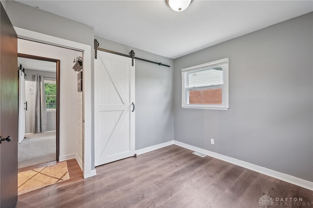 unfurnished bedroom with a barn door and carpet flooring