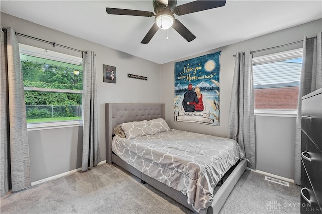 carpeted bedroom with ceiling fan and multiple windows