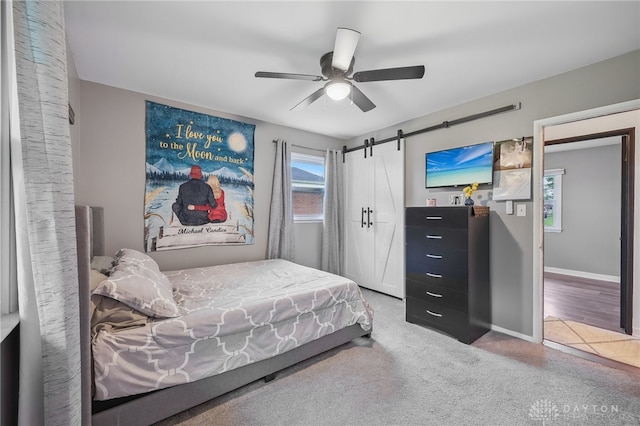 carpeted bedroom featuring ceiling fan and a barn door