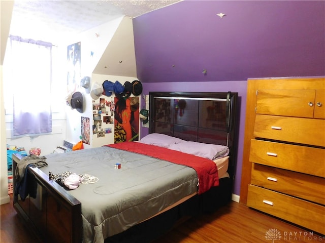 bedroom with lofted ceiling, wood-type flooring, and a textured ceiling