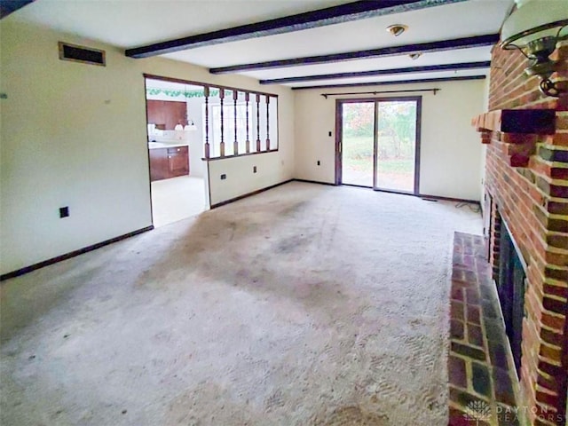 unfurnished living room featuring beamed ceiling, a fireplace, and carpet