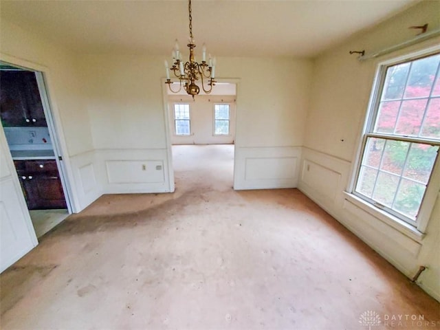 unfurnished dining area featuring a healthy amount of sunlight and a notable chandelier