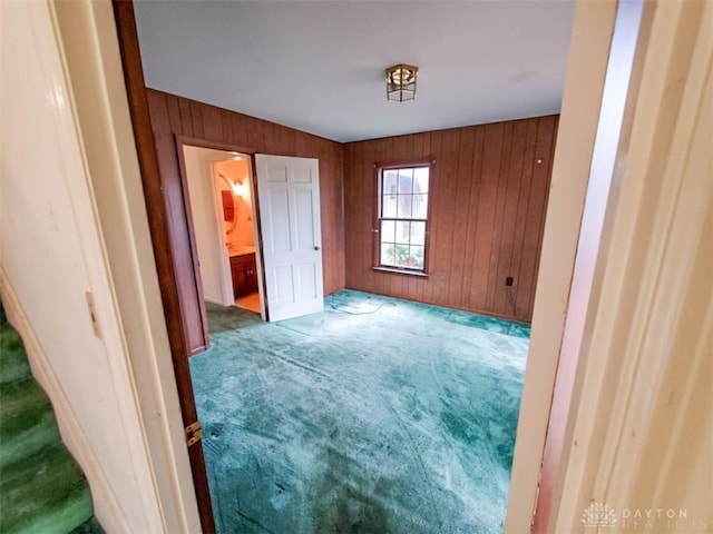 carpeted bedroom featuring wood walls and ensuite bathroom