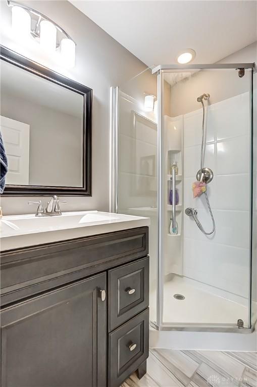 bathroom featuring a shower with shower door and vanity