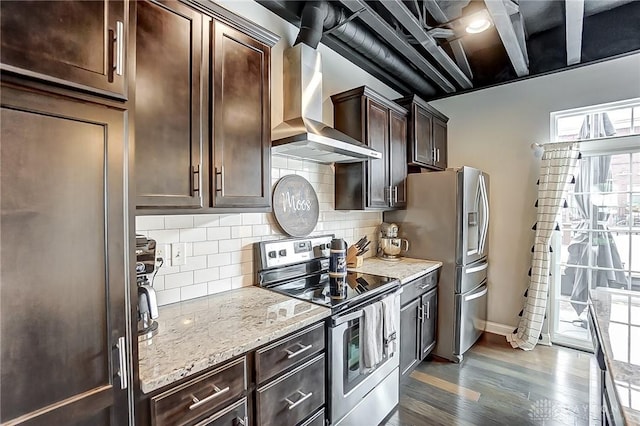 kitchen featuring appliances with stainless steel finishes, dark hardwood / wood-style floors, light stone counters, dark brown cabinets, and wall chimney exhaust hood