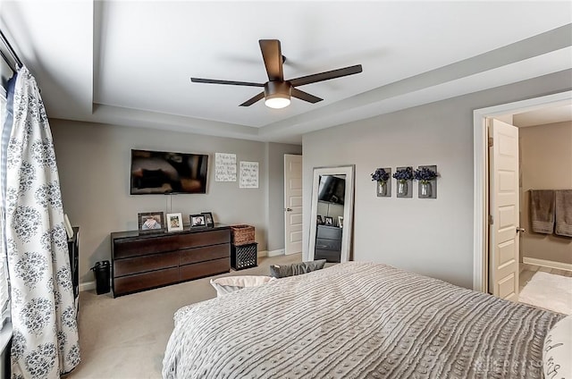 bedroom with ceiling fan, light colored carpet, and a raised ceiling