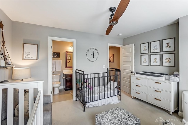 bedroom featuring connected bathroom, a nursery area, and ceiling fan