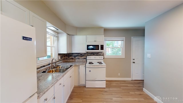 kitchen with white appliances, white cabinetry, sink, and a wealth of natural light