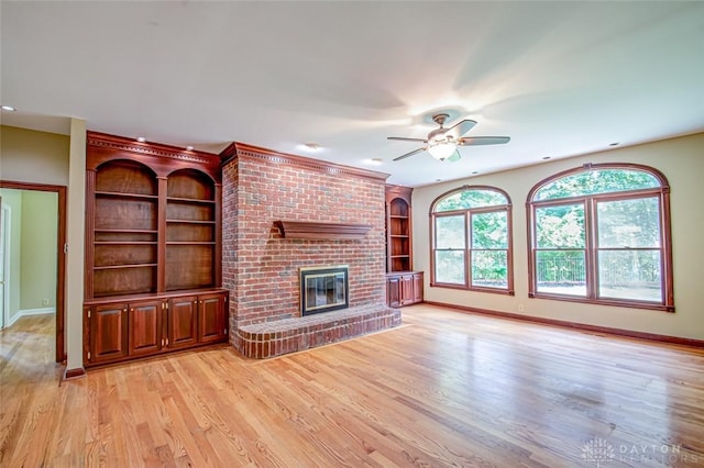 unfurnished living room featuring light hardwood / wood-style floors, built in features, a brick fireplace, and ceiling fan