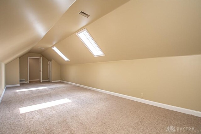 bonus room with lofted ceiling with skylight and light colored carpet