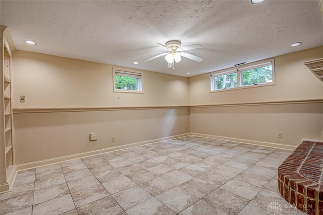 basement with a textured ceiling, ceiling fan, and light tile patterned floors