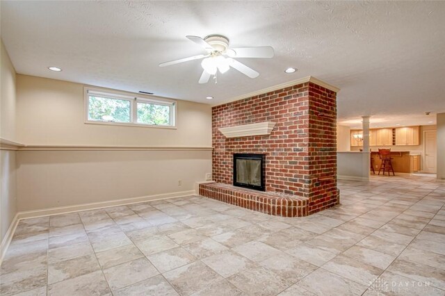 unfurnished living room with light tile patterned flooring, ceiling fan, brick wall, a textured ceiling, and a brick fireplace