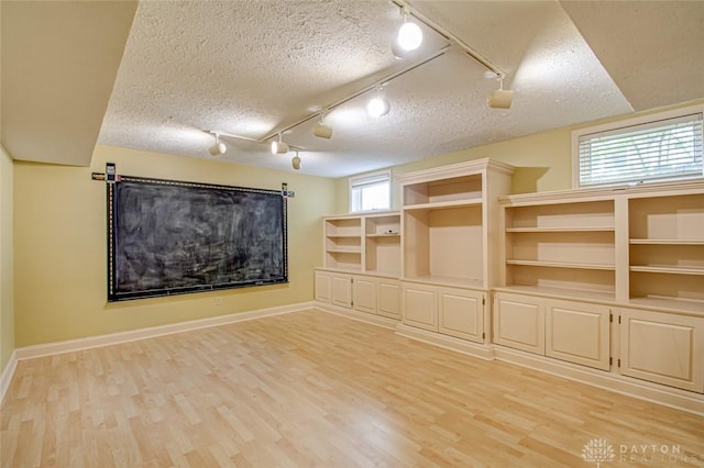 unfurnished room with track lighting, light hardwood / wood-style flooring, and a wealth of natural light