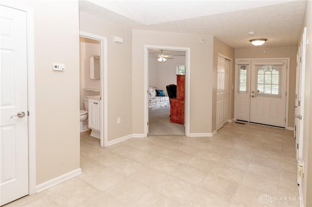 foyer entrance with a textured ceiling and ceiling fan