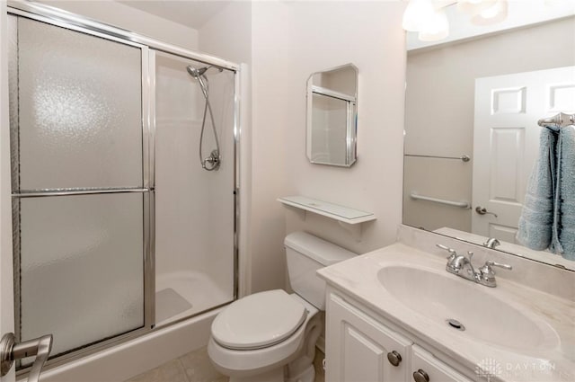 bathroom featuring tile patterned flooring, vanity, toilet, and a shower with shower door