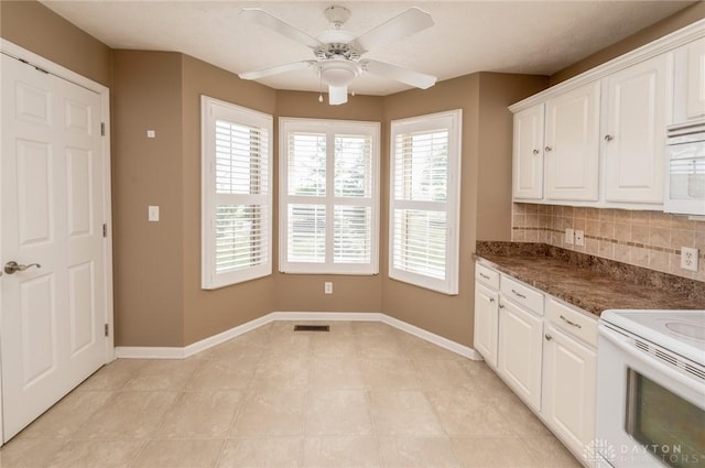 kitchen featuring decorative backsplash, plenty of natural light, white cabinets, and white appliances