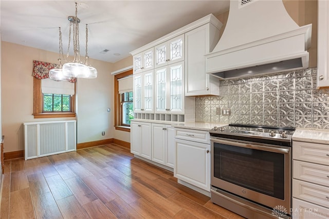 kitchen featuring backsplash, custom range hood, stainless steel range with electric cooktop, light hardwood / wood-style floors, and white cabinets