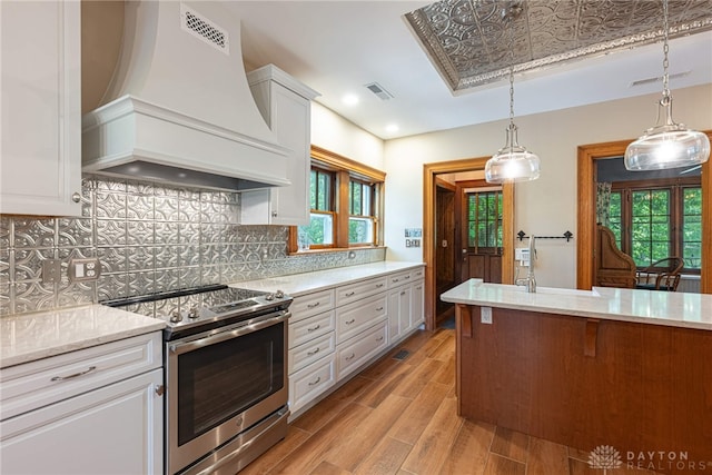 kitchen featuring backsplash, custom range hood, light hardwood / wood-style floors, electric stove, and white cabinetry