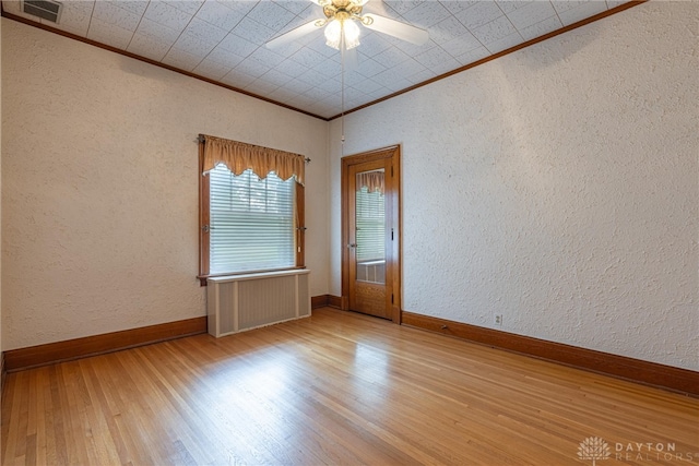 spare room featuring light wood-type flooring, ornamental molding, and ceiling fan