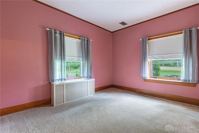 empty room featuring radiator, a healthy amount of sunlight, crown molding, and light colored carpet