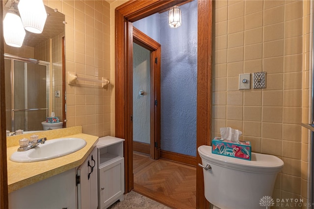 bathroom featuring parquet floors, toilet, vanity, and tile walls