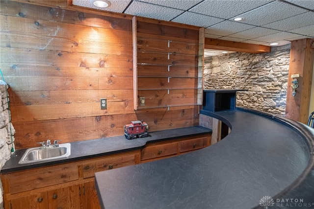 interior space featuring sink, wooden walls, and a drop ceiling