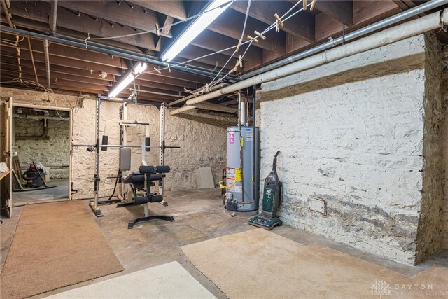 workout room featuring gas water heater and concrete flooring