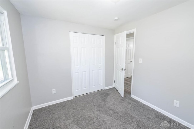 unfurnished bedroom featuring a closet and dark carpet