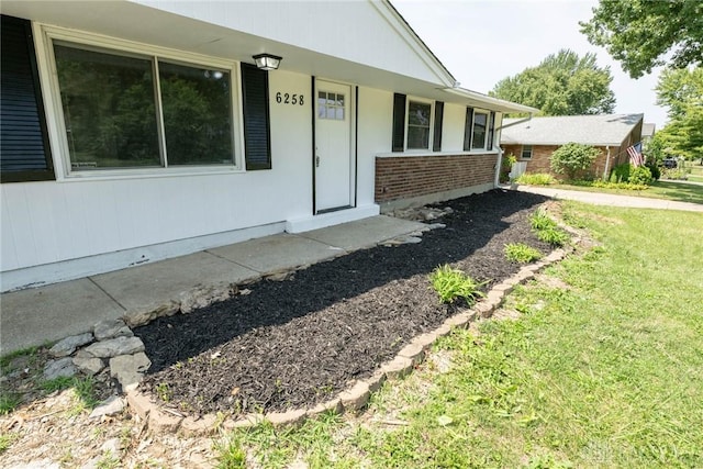 view of exterior entry featuring a lawn