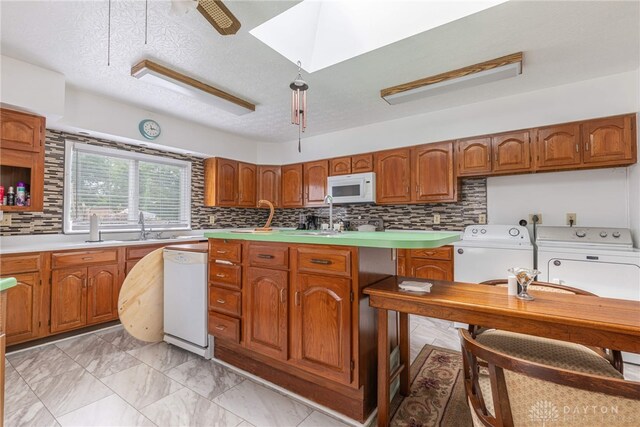 kitchen featuring a textured ceiling, tasteful backsplash, washer and clothes dryer, and white appliances