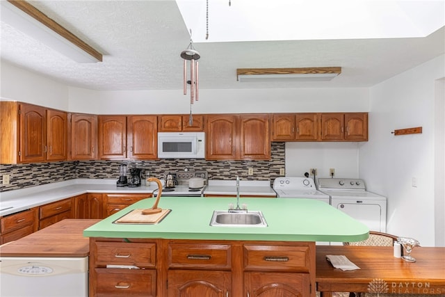 kitchen featuring a kitchen island, washer and dryer, stainless steel stove, sink, and decorative backsplash