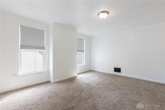 unfurnished room featuring carpet flooring and a textured ceiling