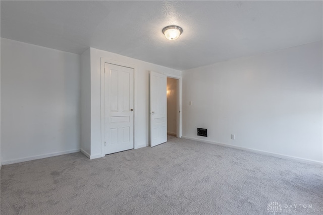 unfurnished bedroom featuring light carpet and a closet