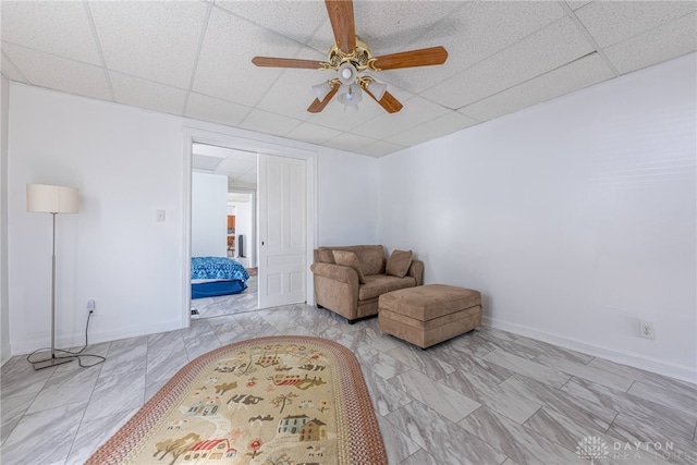 sitting room featuring a drop ceiling and ceiling fan