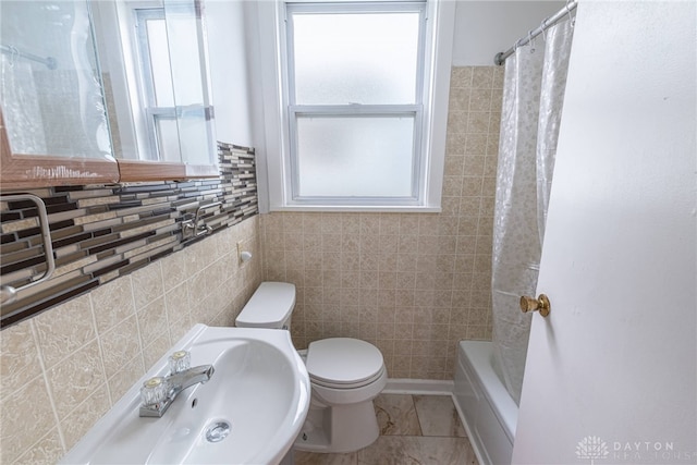 bathroom with toilet, tile walls, and shower / bath combo with shower curtain