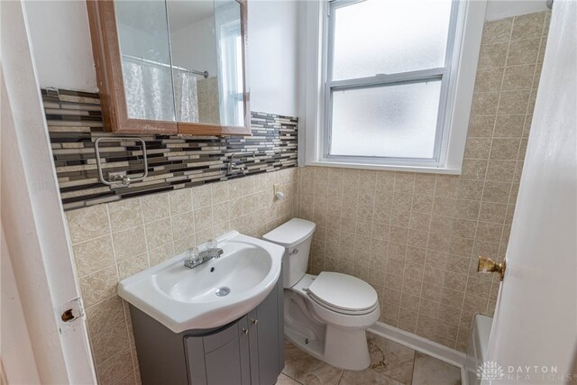 bathroom featuring vanity, tile walls, and toilet