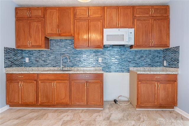 kitchen featuring light stone countertops, sink, and backsplash