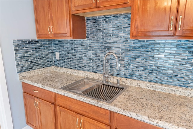 kitchen with light stone counters, sink, and backsplash