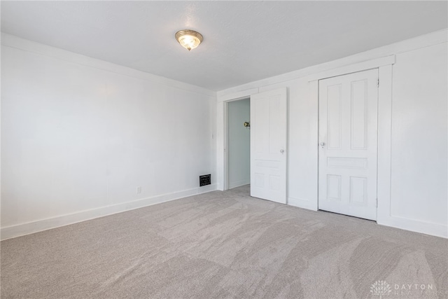 unfurnished bedroom with light colored carpet and a closet