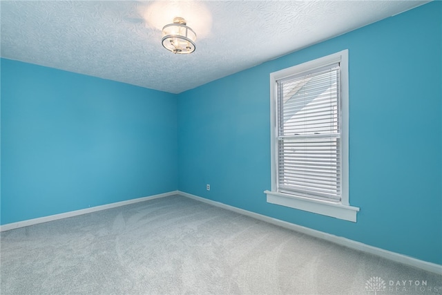 empty room with carpet floors and a textured ceiling