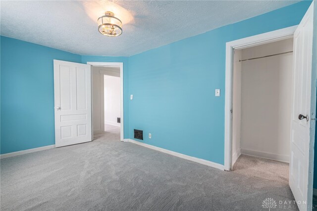 unfurnished bedroom with a textured ceiling and light carpet