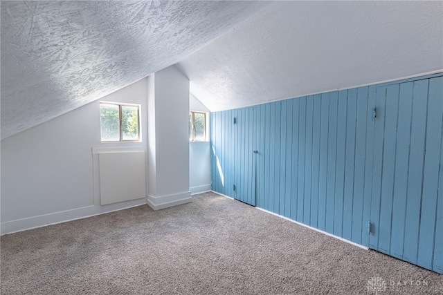 additional living space with carpet, wood walls, and a textured ceiling